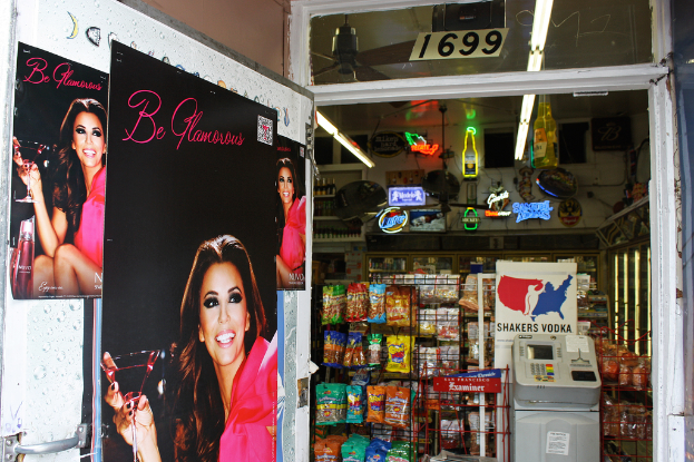 Innenansicht mit Plakaten einer Frau links, einem Laden mit verschiedenen Gegenständen in der Mitte, einem Geldautomaten und einer Texttafel rechts sowie einer Nummernanzeige oben.