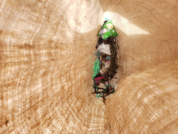 Nahaufnahme eines St"uckes recycelten Papiers auf einem Tisch mit einem Jutestoff im Hintergrund.