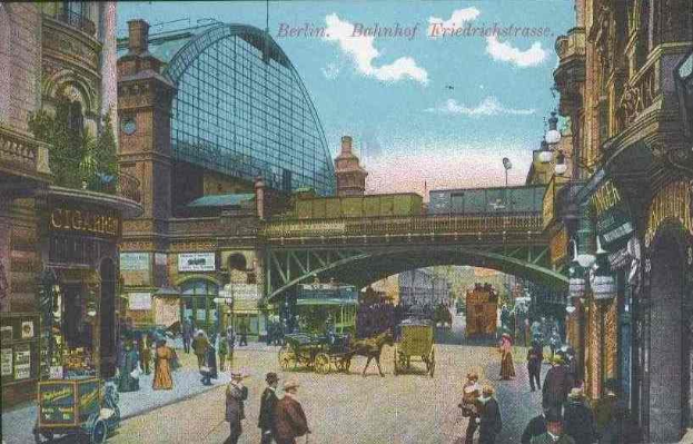Alte Postkarte zeigt eine belebte Stadtstraße in Berlin, Deutschland, mit Fußgängern, Pferdewagen, Gebäuden, Laternenpfählen, einer Brücke und einem bewölkten Himmel mit Text oben.