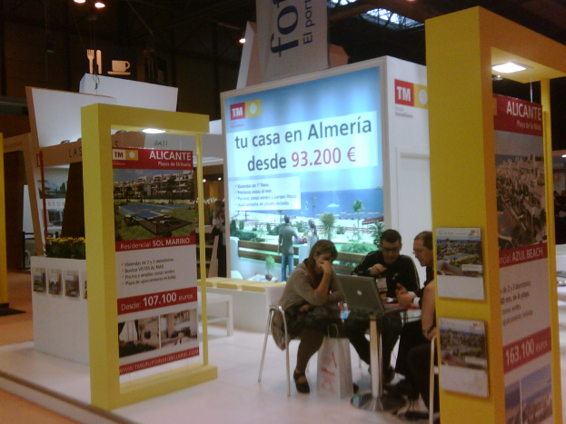 Ein Raum mit Menschen, die an einem Tisch arbeiten und Flyer mit verschiedenen Werbeaussagen umgeben sind.