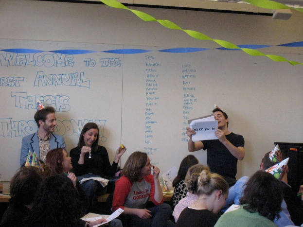 Eine Gruppe von Menschen feiert ihren ersten Jahrestag der Abschlussarbeit, mit Bändern auf dem Dach und einigen Personen mit Mützen.