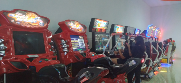 Eine Gruppe von Menschen, die auf Stühlen sitzen und auf mehreren Gaming-Geräten spielen.