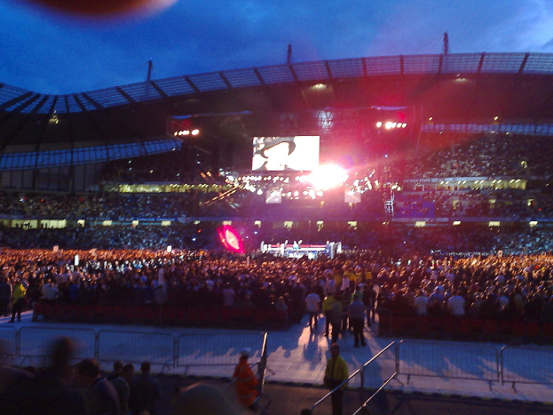 Eine Veranstaltungsstätte mit Menschen, Bühnenlicht und einem Projektionsschirm.