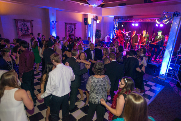 Eine Gruppe von Menschen tanzt mit Musikern und Lichtern im Hintergrund.