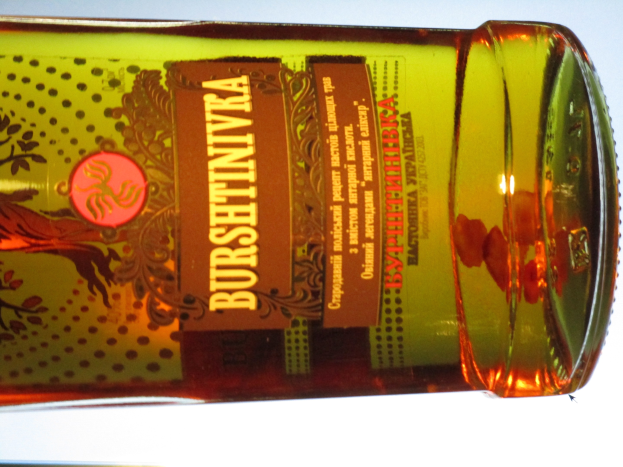 Eine Flasche Olivenöl mit einer goldbraunen Flüssigkeit steht auf einem Tisch, mit einem Etikett.