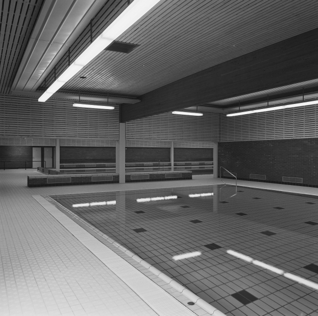 Indoor-Schwimmbad mit klarem Wasser, gefliesten Wänden und Boden, Deckenbeleuchtung und einigen umgebenen Gegenständen in einer ruhigen Umgebung.