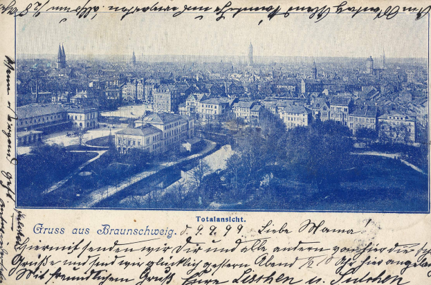 Alte Ansichtskarte mit Stadtansicht von einem Höhenpunkt mit Gebäuden, Bäumen und handgeschriebener Text.