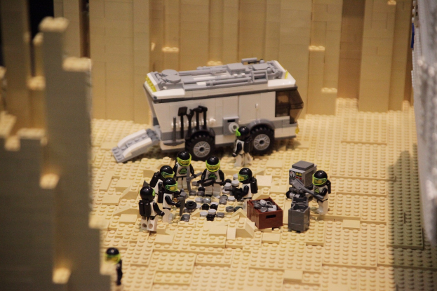 Lego-Modell einer Star-Wars-Szene mit einem Fahrzeug im Vordergrund und einer Wand im Hintergrund sowie einigen verstreuten Lego-Spielzeugen.