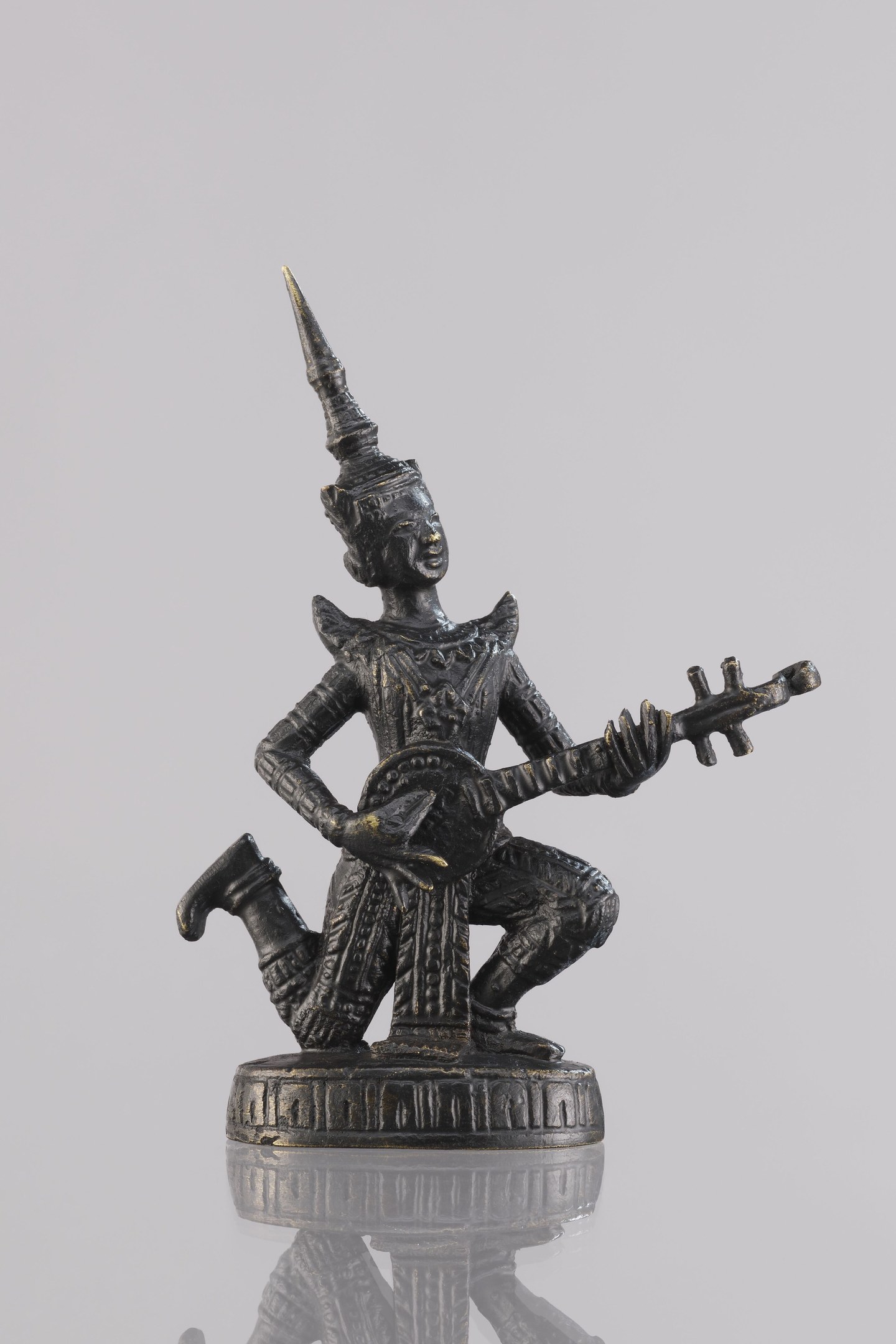 Bronzestatue eines Gitarrespielers vor einem weißen Hintergrund.