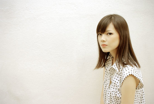 Eine Person in einem weißen und schwarzen Kleid steht neben einer weißen Wand.