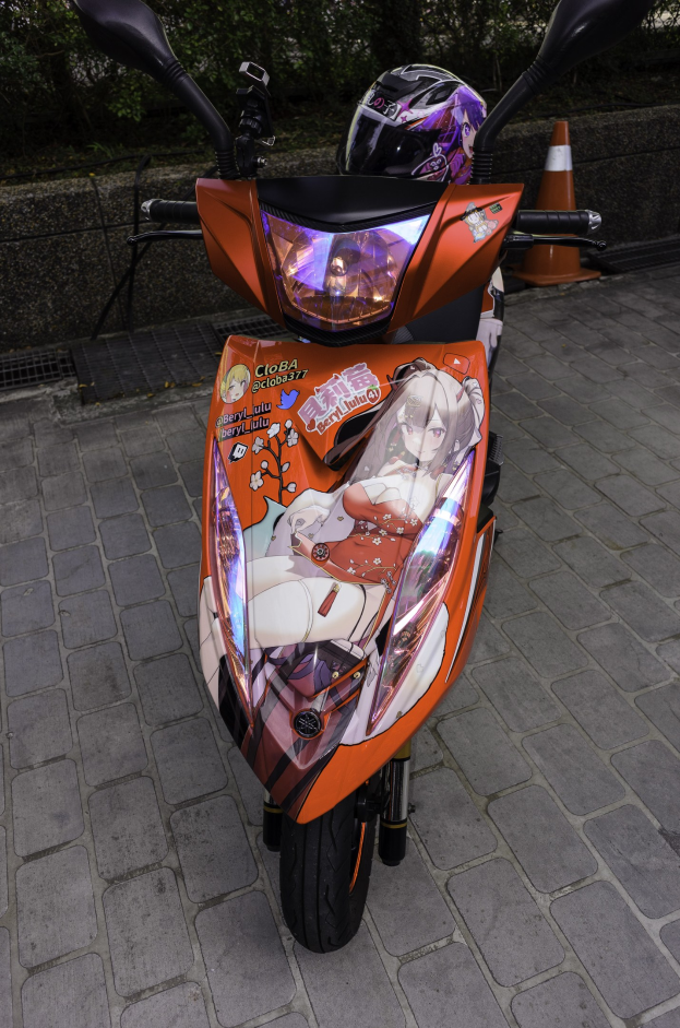 Oranger Roller mit Helm auf der Straße geparkt neben einem Verkehrskegel, einer Wand und Bäumen im Hintergrund.