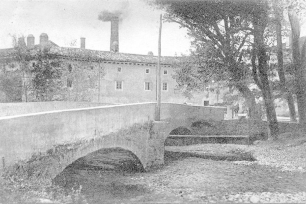 Stadtansicht mit Gebäuden, Bäumen und einer Brücke im Vordergrund, Rauch aus einem Schornstein, unter einem Himmel mit Wasser am Boden.
