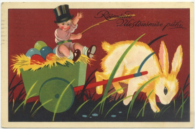 Alte Postkarte mit einem Baby in einem Zylinder, das einen Karren voller bunter Ostereier schiebt, begleitet von einem Hasen, mit handgeschriebenen Ostergrüßen.