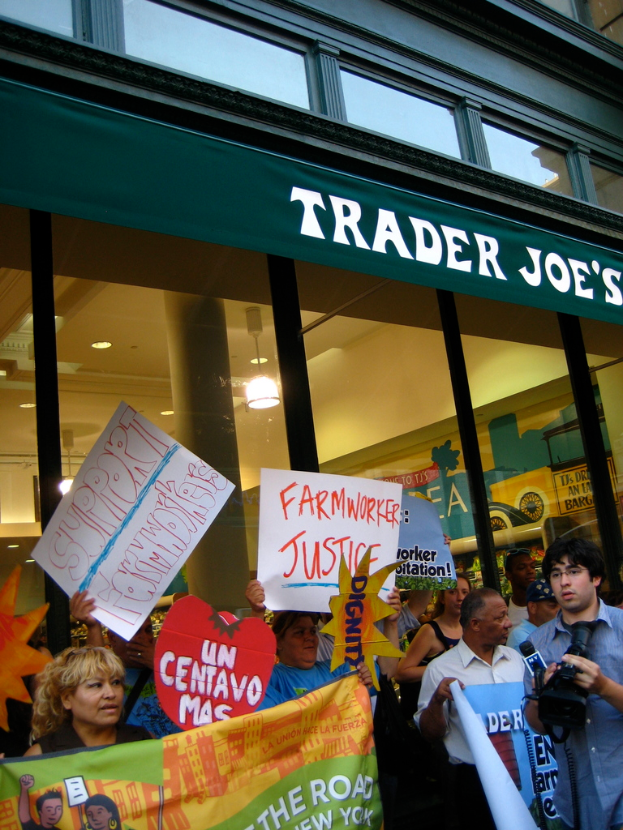 Eine Gruppe von Menschen steht in der Nähe eines Geschäfts und hält Schilder und Plakate in den Händen.