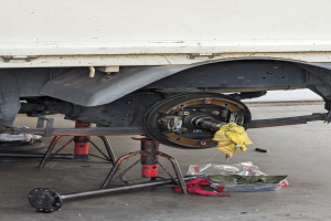 Ein gelber Stoff \c3cre einem in einer Garage geparkten Lkw drapiert, mit Werkzeugen und Gegenst\c3\a4nden, die vor ihm auf dem Boden verstreut sind.