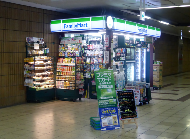 Convenience store interior with "FamilyMart" sign, food racks, refrigerators, informational boards, and visible flooring.