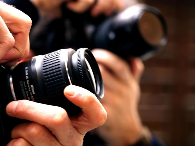 Zwei Personen mit Kameras vor einem unscharfen Hintergrund.