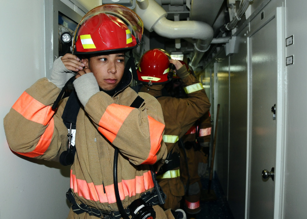 Feuerwehrleute in Uniform in einem Raum mit Rohren und Ausrüstung während eines Trainings.