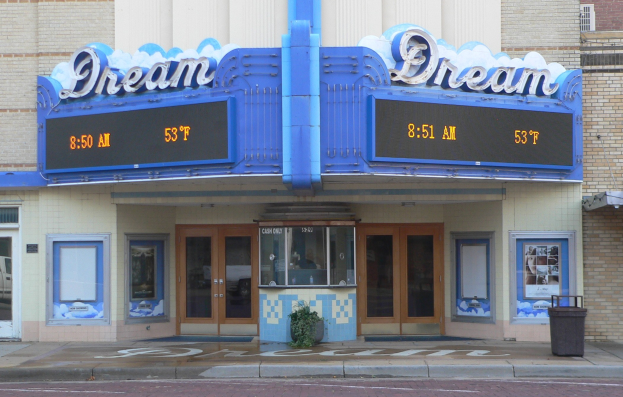 Außenansicht des Dream Theaters in St. Louis, Missouri, mit Glasfenstern und -türen, einem Namensschild, einem Müllcontainer, einem Topf mit einer Pflanze und einer Straße unten.
