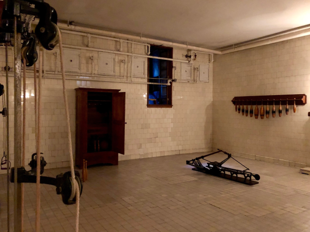 Ein unordentlicher Raum im ehemaligen Gefängnis St. Louis mit Seilen, Maschinen und anderem Equipment, einem Schrank, einem Fenster und einer Deckenlampe.