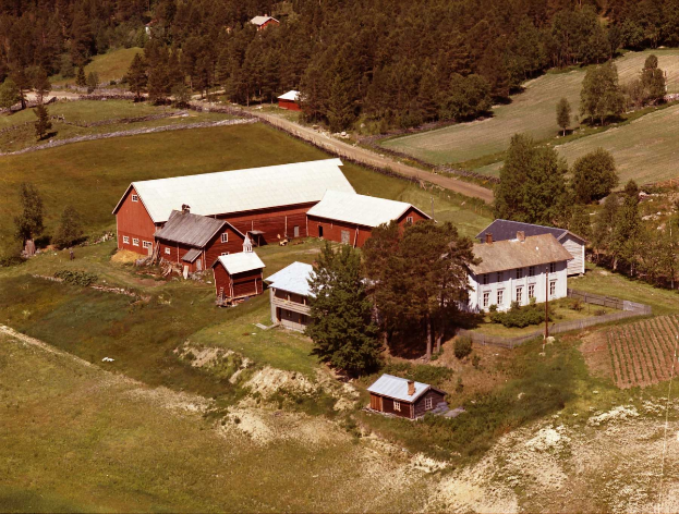 Eine Luftaufnahme eines Hofes in einem Feld, umgeben von Häusern, Bäumen, Pflanzen, Gras, Pfählen und einer Straße, gelegen in den Hügeln von Montana.