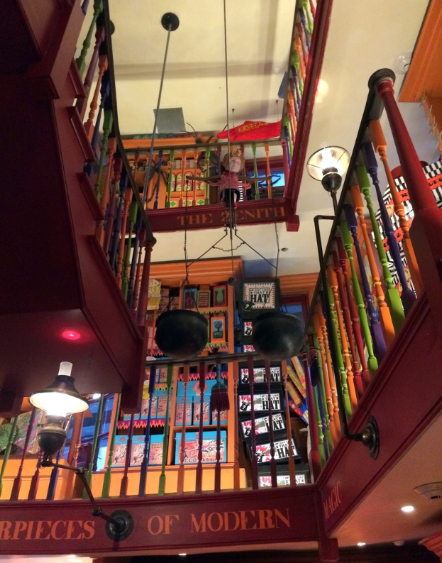 Ein Gebäude mit Treppe, einem Zaun, Lampen, einer Puppe, einem Schild und einem Dach.