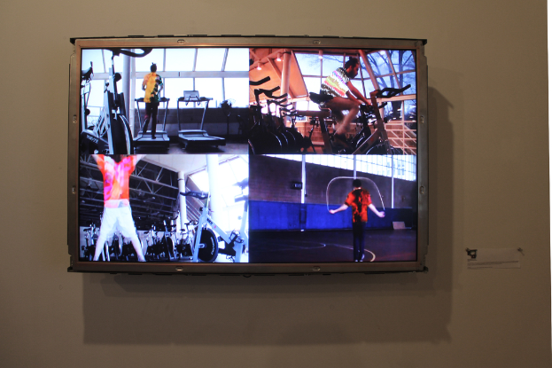 Ein an der Wand montierter Fernseher, auf dem Menschen zu sehen sind, die Sport treiben.