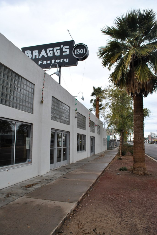 Ein GebÃ¤ude mit einer Fahne, auf der "Braggs Factory" steht, umgeben von BÃ¤umen.