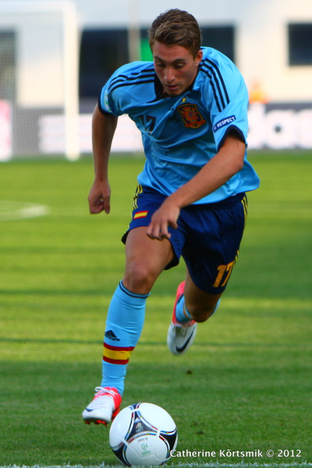 Mann in blauem T-Shirt beim Fußballspielen auf einem Feld.