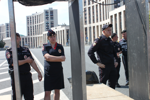 Eine Gruppe von Polizisten in Uniform auf einer Straße mit Gebäuden, Bäumen und einem klaren Himmel im Hintergrund.