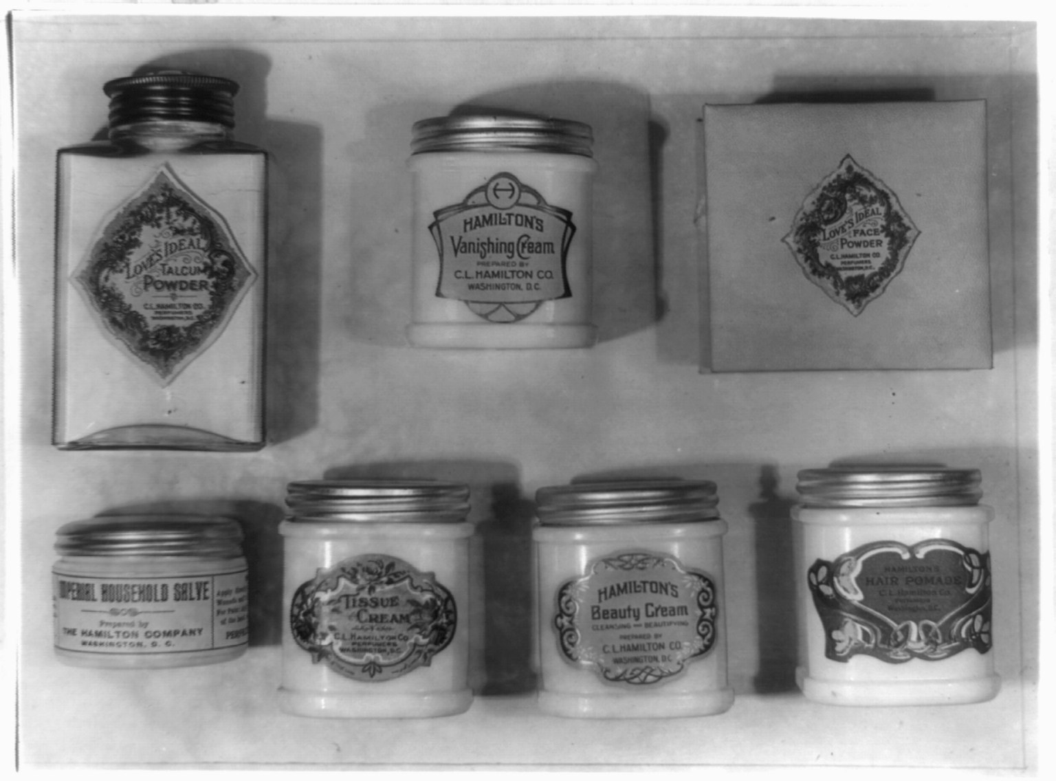 Schwarz-weißes Foto eines Regals mit ordentlich angeordneten Cremetöpfchen, die alle mit verschiedenen Typen beschriftet sind.