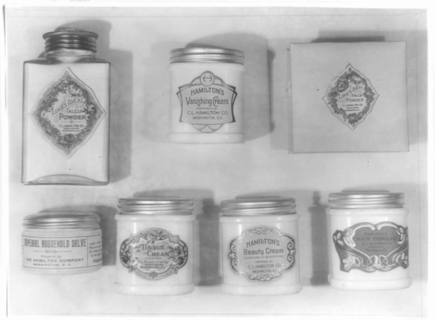 Schwarz-weißes Foto eines Regals mit ordentlich angeordneten Cremetöpfchen, die alle mit verschiedenen Typen beschriftet sind.