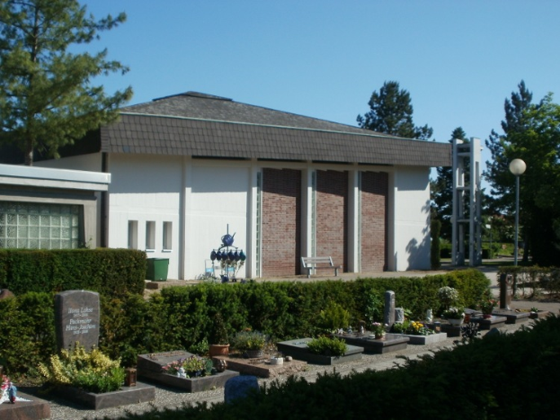 Ein Haus mit Dach, Fenstern, Säulen und einer Tür, umgeben von Pflanzen, Gras, einer Statue, einer Bank, Pfosten, einem Straßenpfosten, einem Mülleimer, Bäumen und einem bewölkten Himmel, mit einem Friedhof vorne, der zahlreiche Grabsteine aufweist.