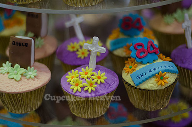 Ein Buch und ein heiliges Kreuzsymbol werden auf einem Cupcake platziert, mit anderen Cupcakes im Hintergrund.