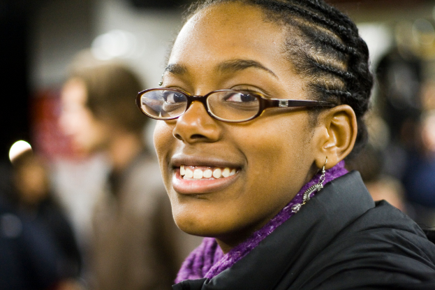 Eine Frau mit einem freundlichen Gesichtsausdruck, die eine Brille trägt, mit einem unscharfen Hintergrund.