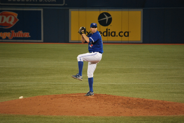 Ein Spieler steht auf dem Boden und hält einen Ball, im Hintergrund ein großes Banner mit Text und Bildern.