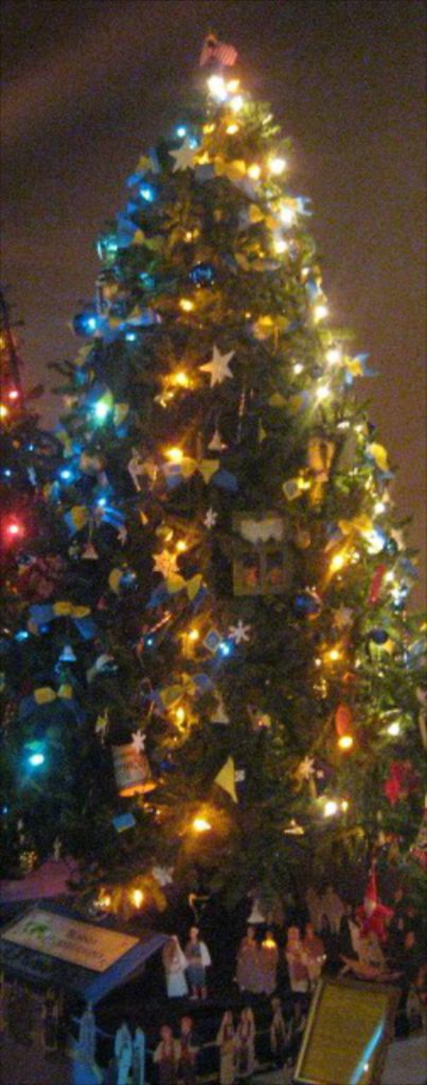 Ein belebter Marktplatz mit Menschen und St√§nden auf beiden Seiten und Plakaten in der Mitte.