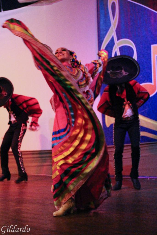 Menschen auf einer Bühne mit Kostümen, mit einem Vorhang mit einem Bild im Hintergrund.