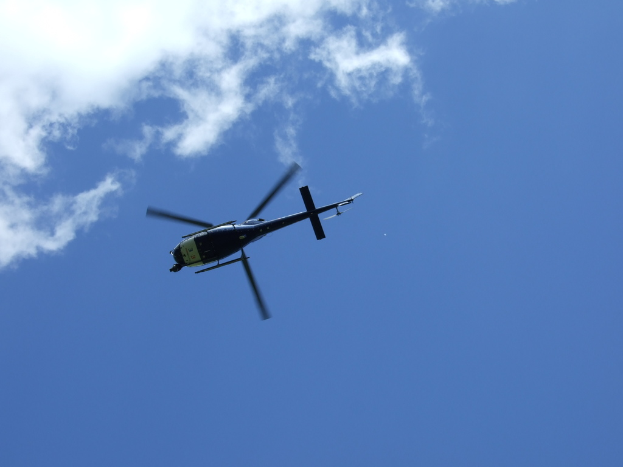 Ein Hubschrauber fliegt unter einem blauen Himmel.