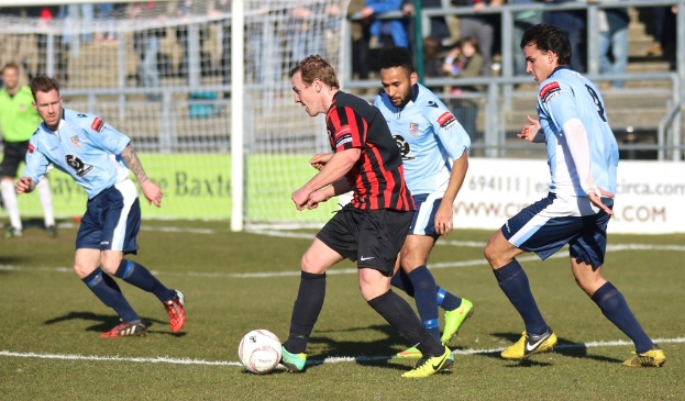 Eine Gruppe von Menschen, die mit einem Fussball auf einem Feld spielen.