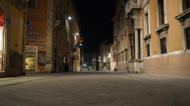 Eine nächtliche Straßenszene mit Gebäuden auf beiden Seiten, einem Geschäft auf der linken Seite und Lichtern in der Mitte.