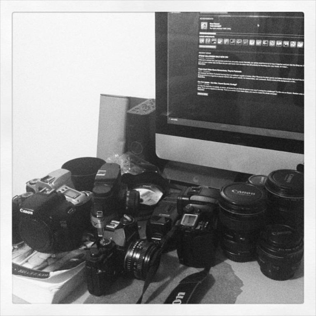 Ein Tisch mit mehreren Kameras, einem Computer, einer CPU und anderen Gegenständen.