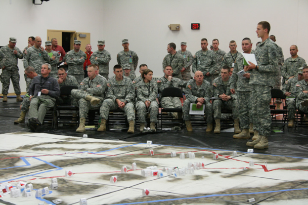 Eine Gruppe von Menschen in der Nähe eines Ausgangsschilds an einer Wand, einer Tür und einer Karte auf dem Boden.