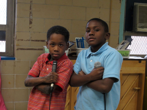 Zwei Kinder stehen und halten Mikrofone in den Händen.