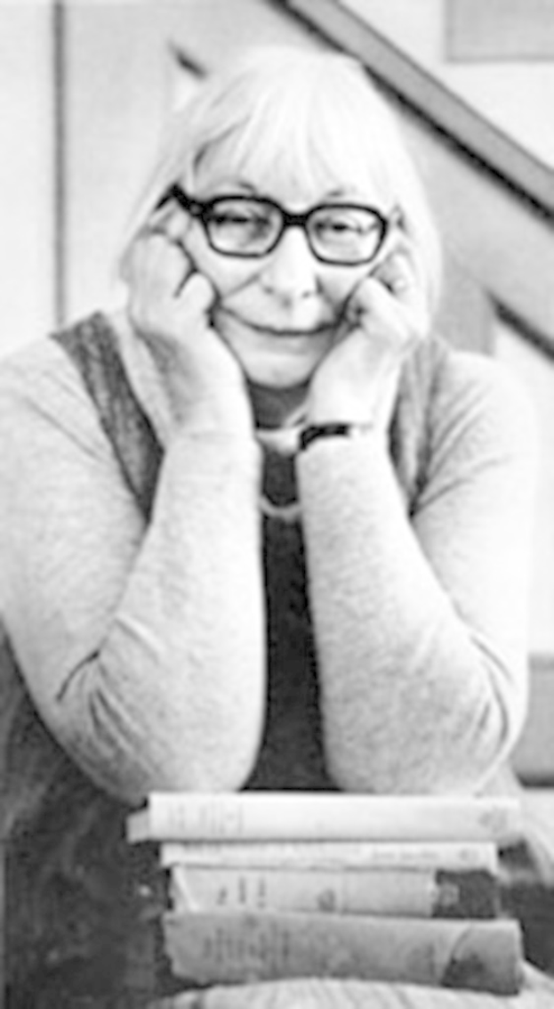 Ein Schwarz-Weiß-Bild einer Frau, die vor einer Sammlung von Büchern steht.